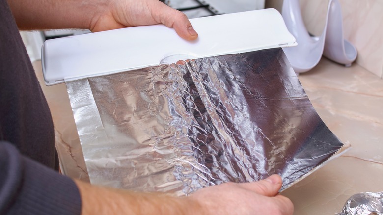 Person tearing aluminum foil