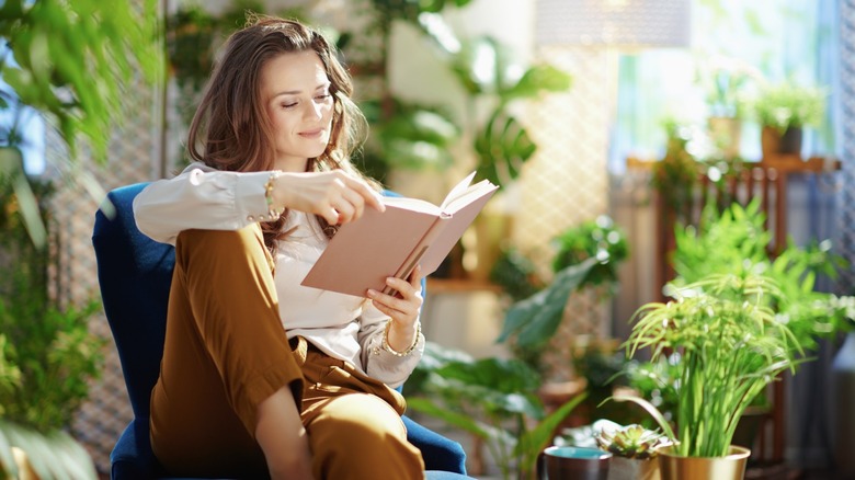 Woman surrounded by plants reading book