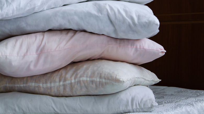 Dirty pillows stacked on bed