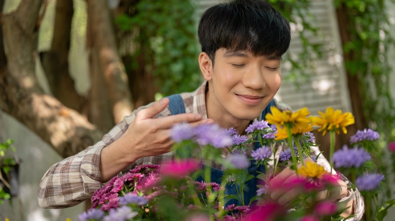 man smelling flowers in garden