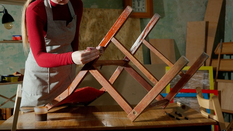 woman staining a wooden chair