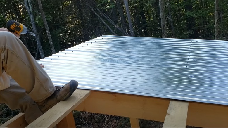 Man building shade out of corrugated metal