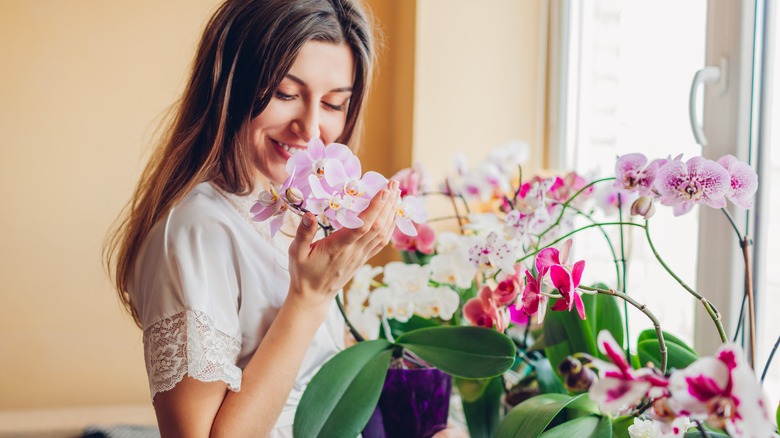 woman smiling and smelling orchids