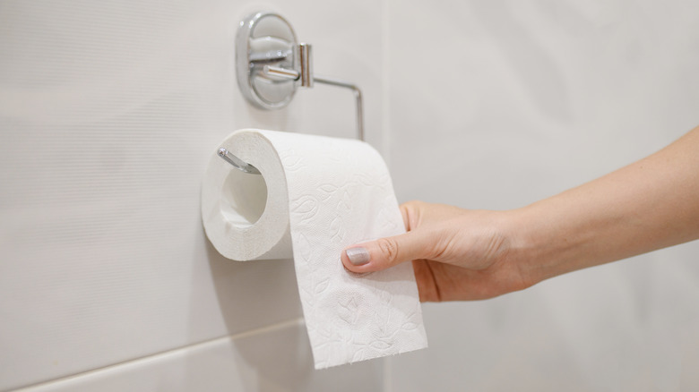 woman pulling sheet of toilet paper